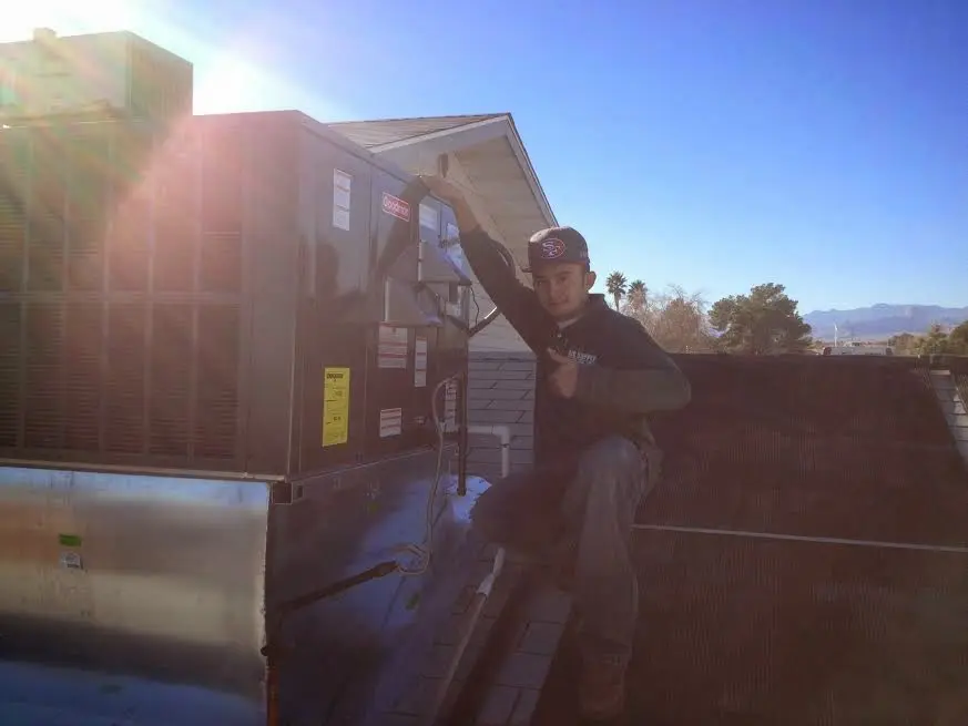 HVAC technician performing Heat Pump Repair on a rooftop unit in Normal